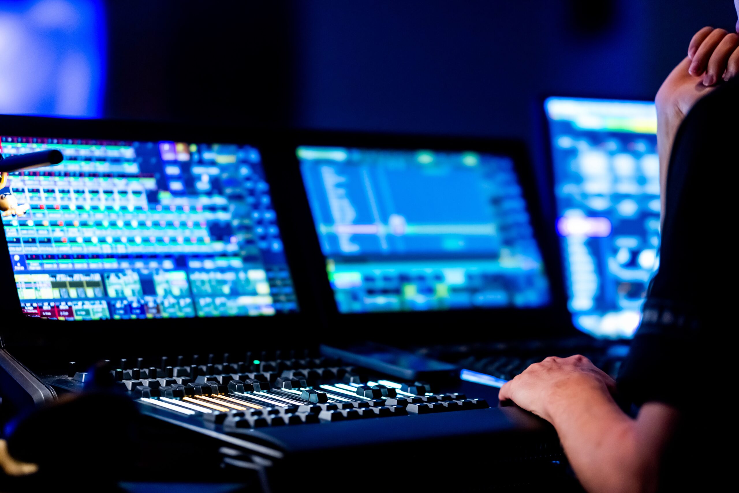 Audio engineer operating a mixing console with monitors at a live event