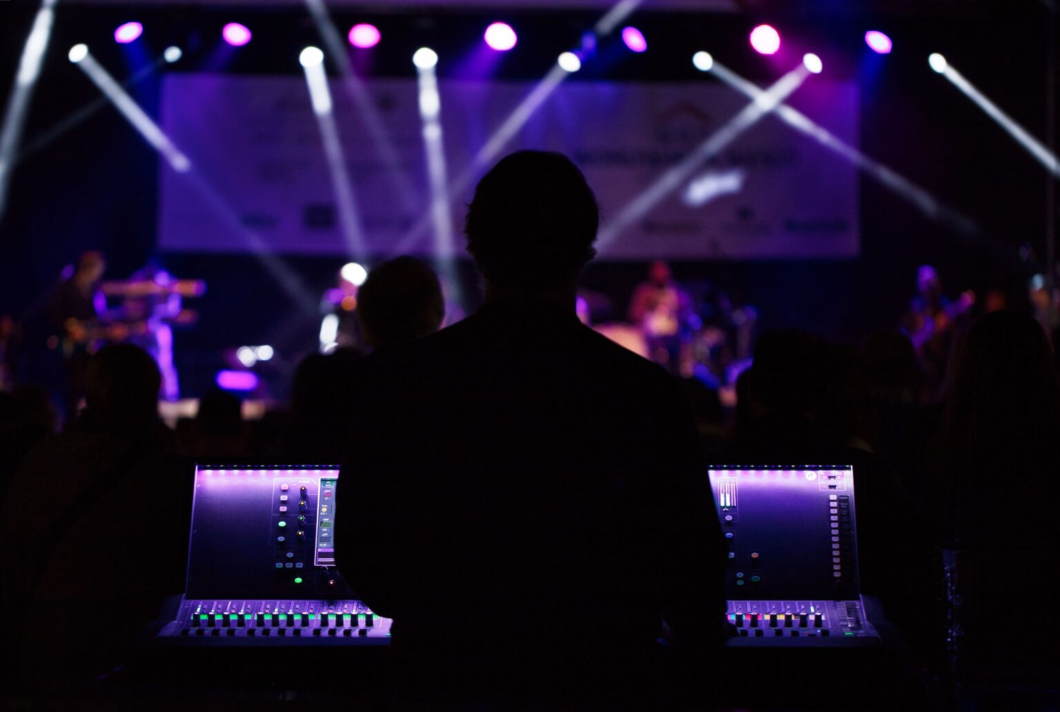 Illustrative photograph of a concert stage with lighting and a front-of-house mixing position.