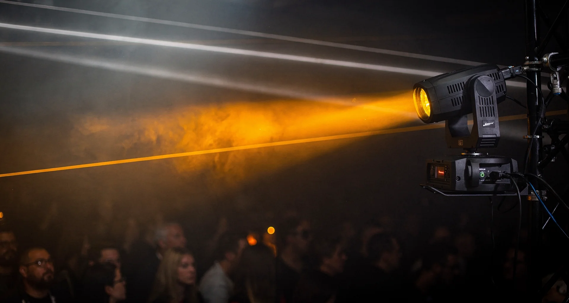 Illustrative photograph of moving-head stage lights on a truss during a performance.